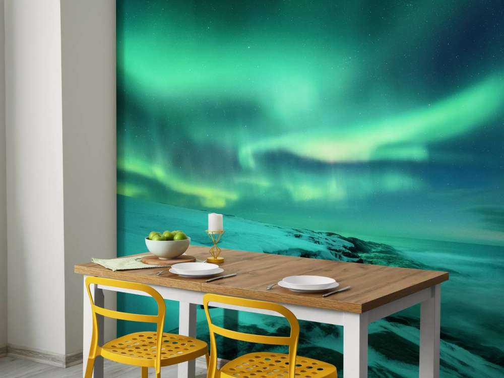 Des aurores boréales vertes au-dessus des rochers enneigés