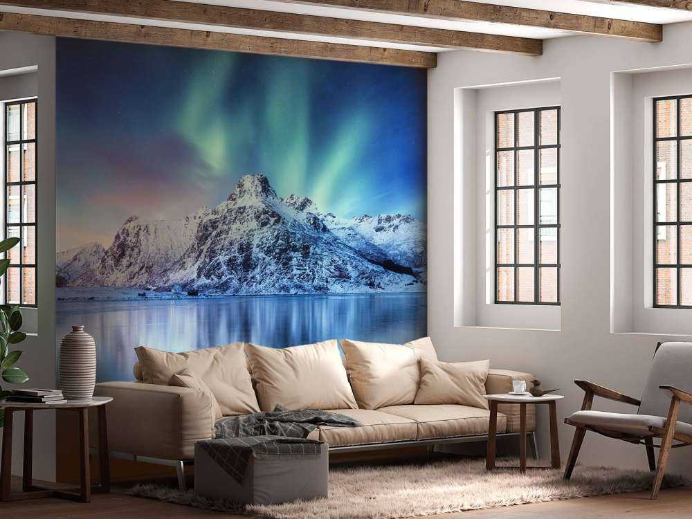 Des aurores boréales au-dessus d'un océan et de montagnes gelés