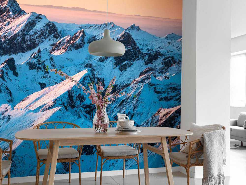 Lever du soleil sur un massif montagneux enneigé.