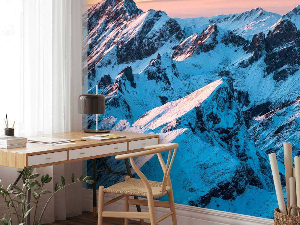 Lever du soleil sur un massif montagneux enneigé.